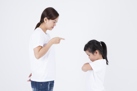 Multicultural family mother giving daughter a good scolding isolated on whiteの写真素材