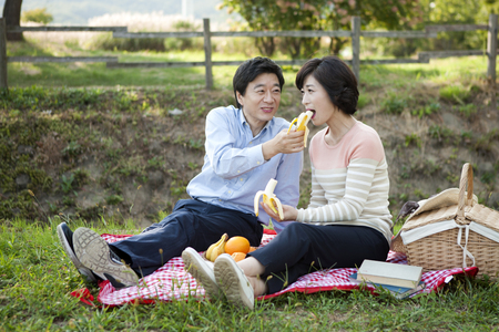 Asian middle aged couple are on a picnic on grass outdoorの写真素材