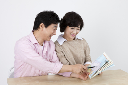 Asian middle aged couple with map isolated on whiteの写真素材