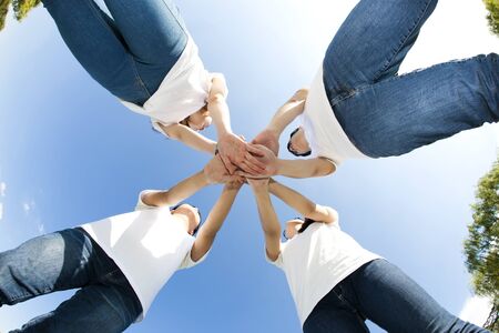 From below Happy Asian people group with their arms joined on grassの写真素材