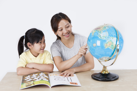 Multicultural family mother and daughter with globe isolated on whiteの写真素材