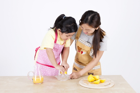 Multicultural family mother and daughter making lemon juice isolated on whiteの写真素材
