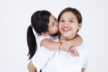 Multicultural family mother giving daughter ride on back isolated on whiteの写真素材