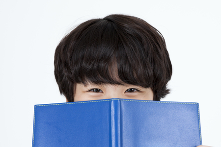 Asian cute boy with blue book isolated on whiteの写真素材