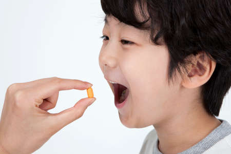 Asian cute boy taking medicine isolated on white