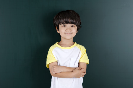 Asian boy crossed his arms on blackboard background isolated on whiteの写真素材