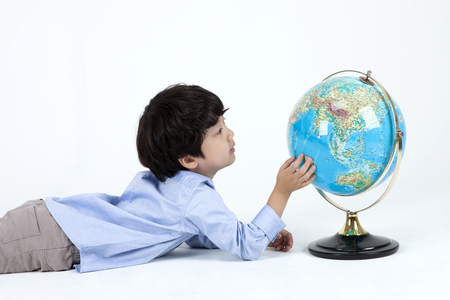 Asian cute boy lying with globe isolated on whiteの写真素材
