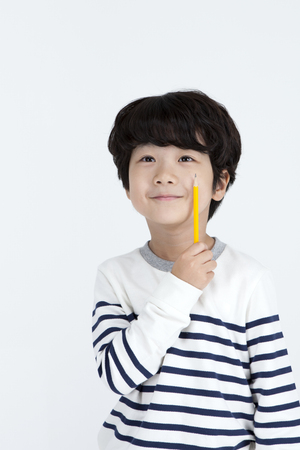 Asian cute boy with pencil isolated on whiteの写真素材