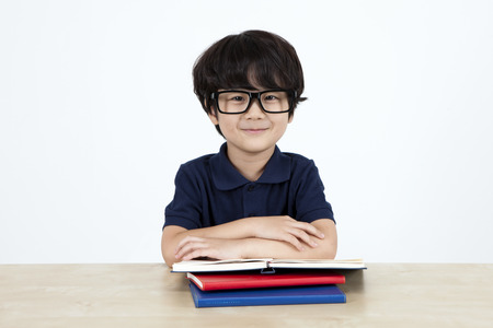 Asian cute boy with notebooks on the desk isolated on whiteの写真素材
