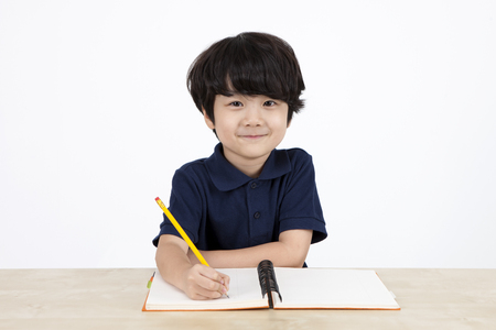 Asian cute boy writing notebook isolated on whiteの写真素材
