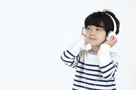 Asian cute boy listening music isolated on whiteの写真素材