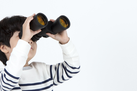 Asian cute boy using telescope isolated on whiteの写真素材