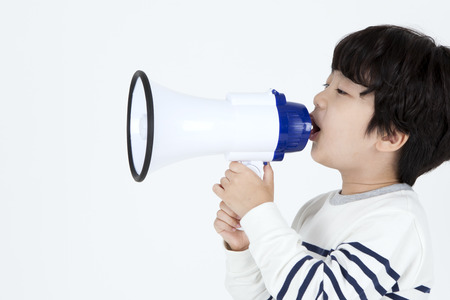 Asian cute boy shouting with loudspeaker isolated on whiteの写真素材