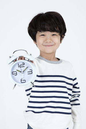Asian cute boy with clock isolated on whiteの写真素材