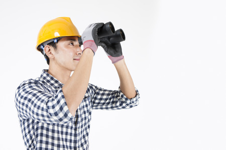 Asian engineers in yellow helmet looking through with telescope isolated on whiteの写真素材