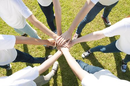 Closeup Happy Asian people group with their arms joined on grassの写真素材