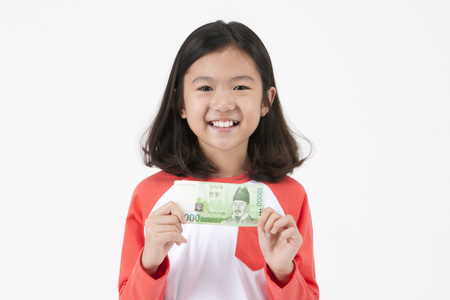 Asian female child pointing with money isolated on whiteの写真素材