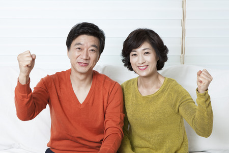 Asian middle aged couple in cheer up gesture on sofa bedの写真素材