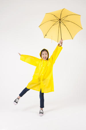 Asian female child in raincoat with umbrella isolated on whiteの写真素材