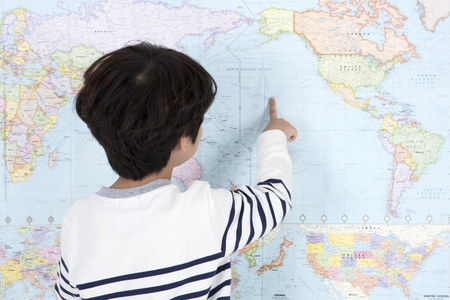 Asian smart boy reading and checking map isolated on whiteの写真素材