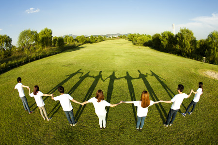 Rear view Happy Asian people group holding their hands on grass with shadowの写真素材