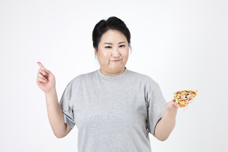 Asian overweight woman rejecting pizza isolated on whiteの写真素材