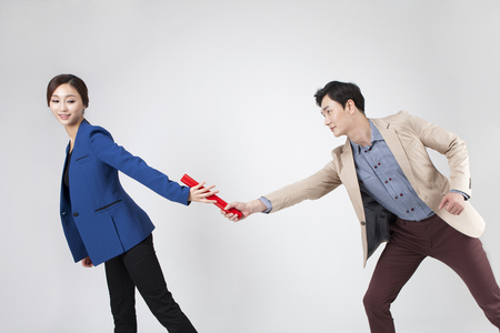 Asian business couple run a relay with baton isolated on whiteの写真素材