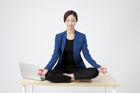Asian business woman meditating on the desk isolated on whiteの写真素材