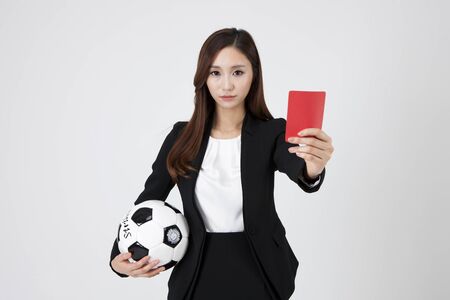 Asian business woman with soccer ball and red card isolated on whiteの写真素材