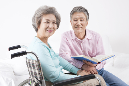 Asian old aged couple reading book isolated on whiteの写真素材