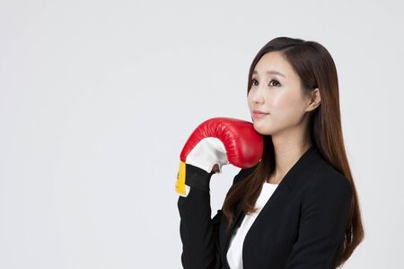 Asian business woman thinking with boxing glove isolated on whiteの写真素材