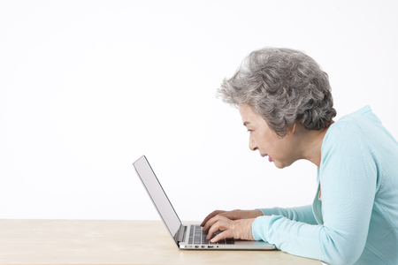 Asian old aged woman using laptop isolated on whiteの写真素材