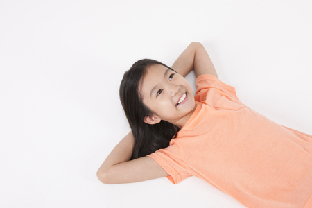 Top view Asian female child lying back on the studio isolated on whiteの写真素材