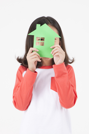Asian female child with paper house cutout isolated on whiteの写真素材