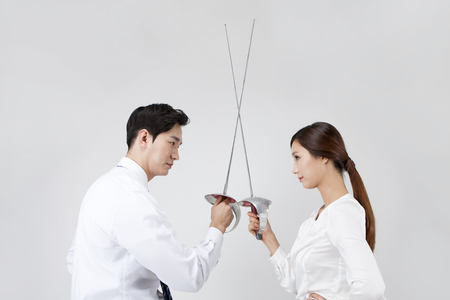 Asian business couple playing fencing isolated on white