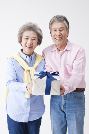 Asian old aged couple with gift isolated on whiteの写真素材