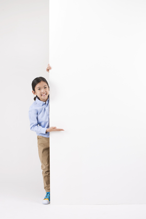 Asian female child with white board isolated on whiteの写真素材