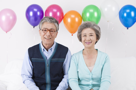Asian old aged couple with balloons isolated on whiteの写真素材