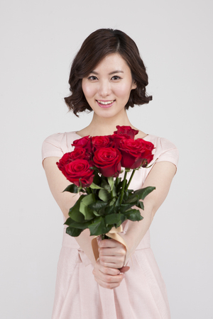 Asian young woman with bouquet isolated on whiteの写真素材
