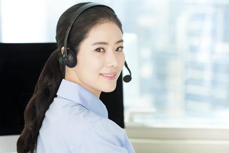 Closeup Asian female telemarketer in officeの写真素材