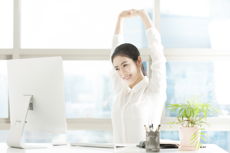 Asian business woman doing arm stretching in officeの写真素材