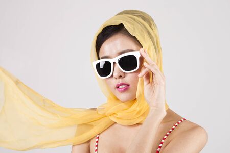 Asian retro woman in sunglasses and yellow scarf isolated on whiteの写真素材