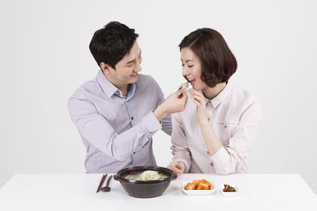 Asian business couple eating samgyetang isolated on whiteの写真素材