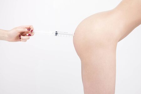 Closeup photo of Asian woman having an injection on buttock isolated on whiteの写真素材