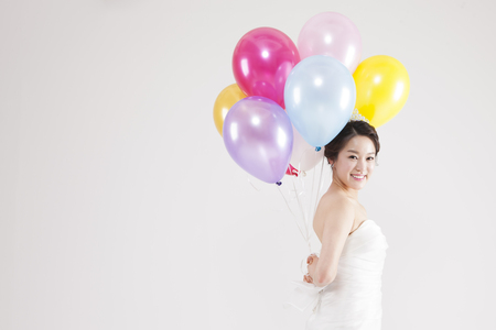 Asian beautiful bride with colorful balloons isolated on whiteの写真素材
