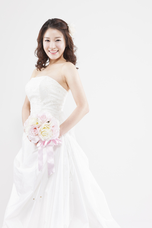 Asian beautiful bride with bouquet isolated on whiteの写真素材