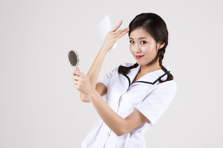 Asian retro woman looing at camera with mirror isolated on whiteの写真素材