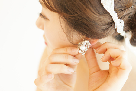 Asian beautiful bride wearing a pair of earrings isolated on whiteの写真素材