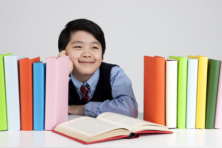 Asian elementary school boy with book isolated on white