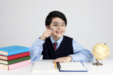 Asian elementary school boy with magnifier isolated on whiteの写真素材